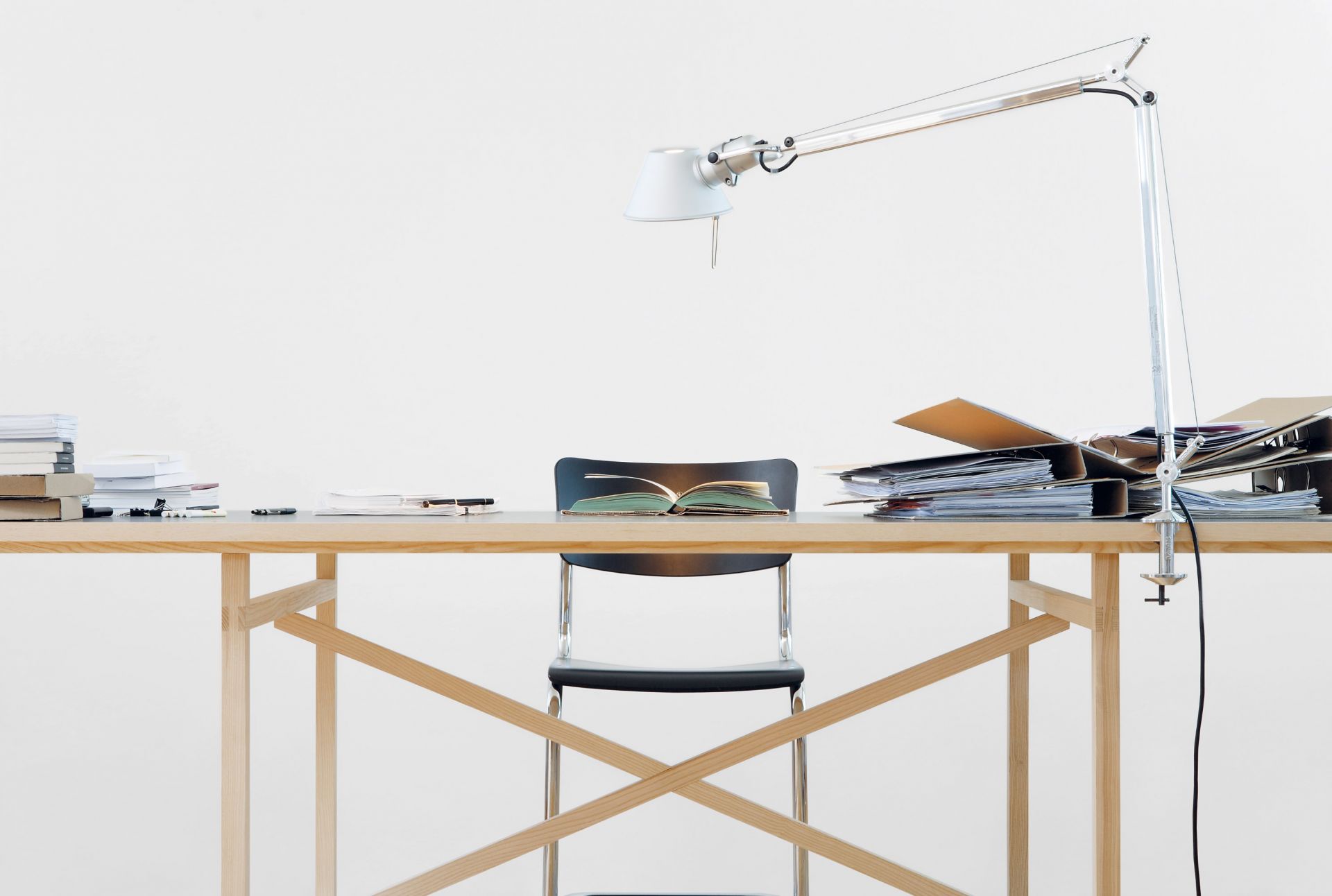 Egon Tisch von Nils Holger Moormann aus Holz mit Schreibtischlampe, Stuhl, Buch und Ordner.