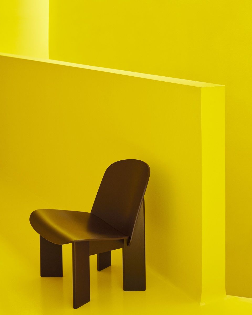 Brauner Chisel Lounge Chair Sessel von Hay vor gelbem Hintergrund, modernes Möbeldesign.
