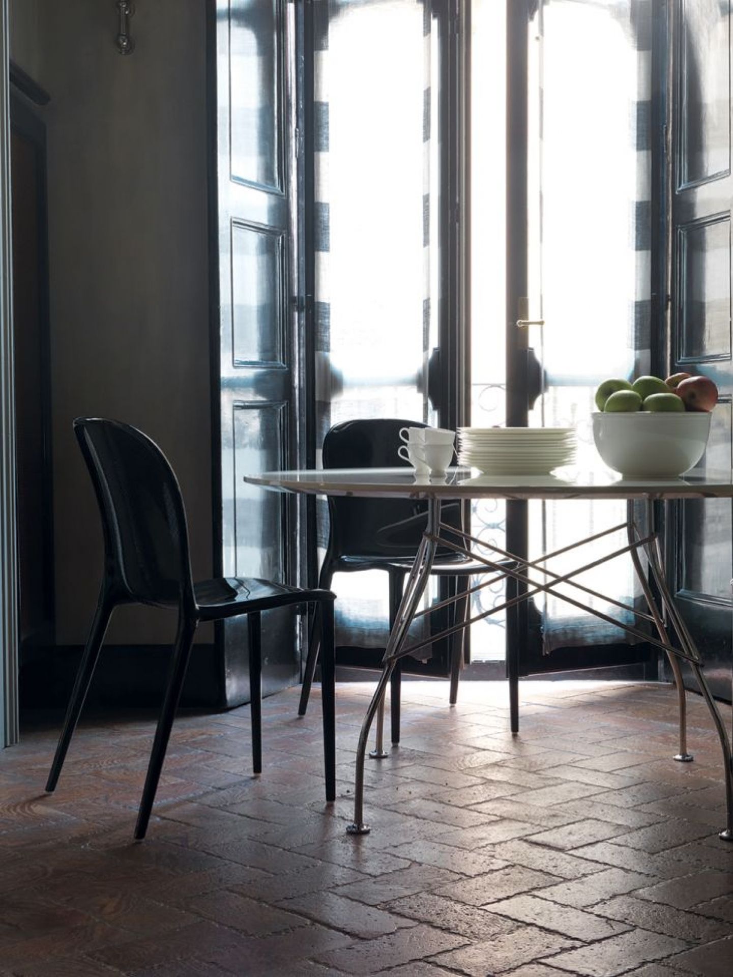 Glossy Kartell Tisch mit runder, marmorierter Steinzeugplatte und schwarzen Stühlen in einem Esszimmer.