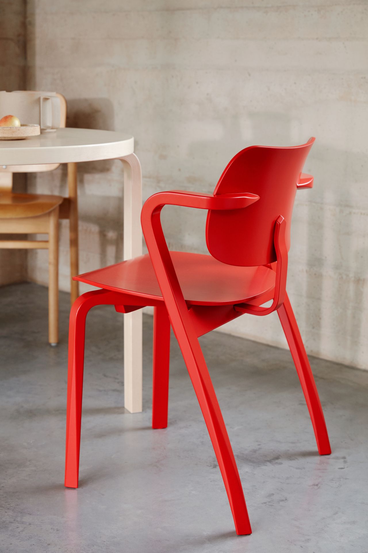 Nahaufnahme des roten Aslak Chair Stuhls von Artek mit Armlehnen und minimalistischem Design.