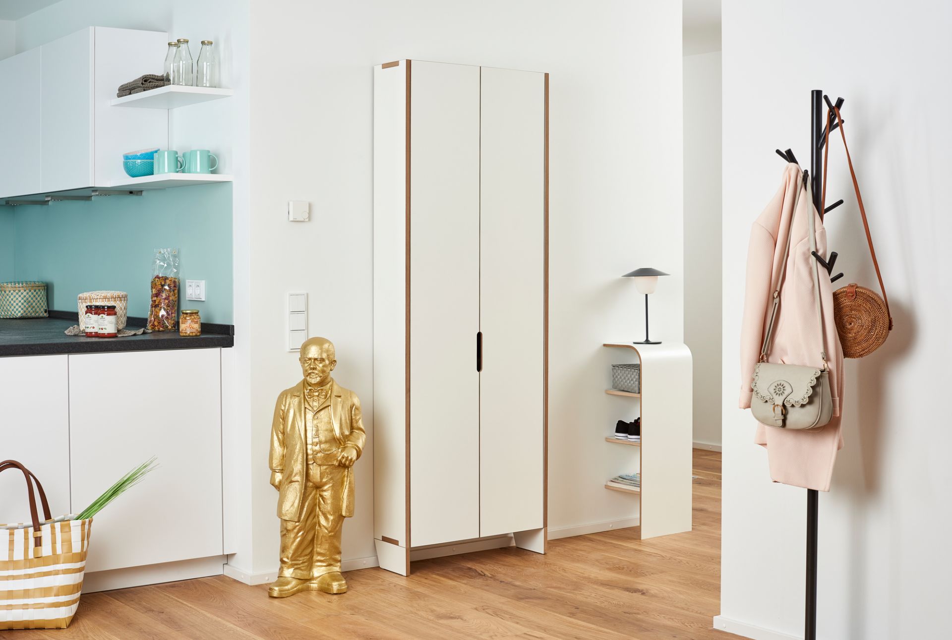 Moderner, weißer Tojo Flachmann Schuhschrank aus Holz im Flur mit Garderobe und goldener Statue.