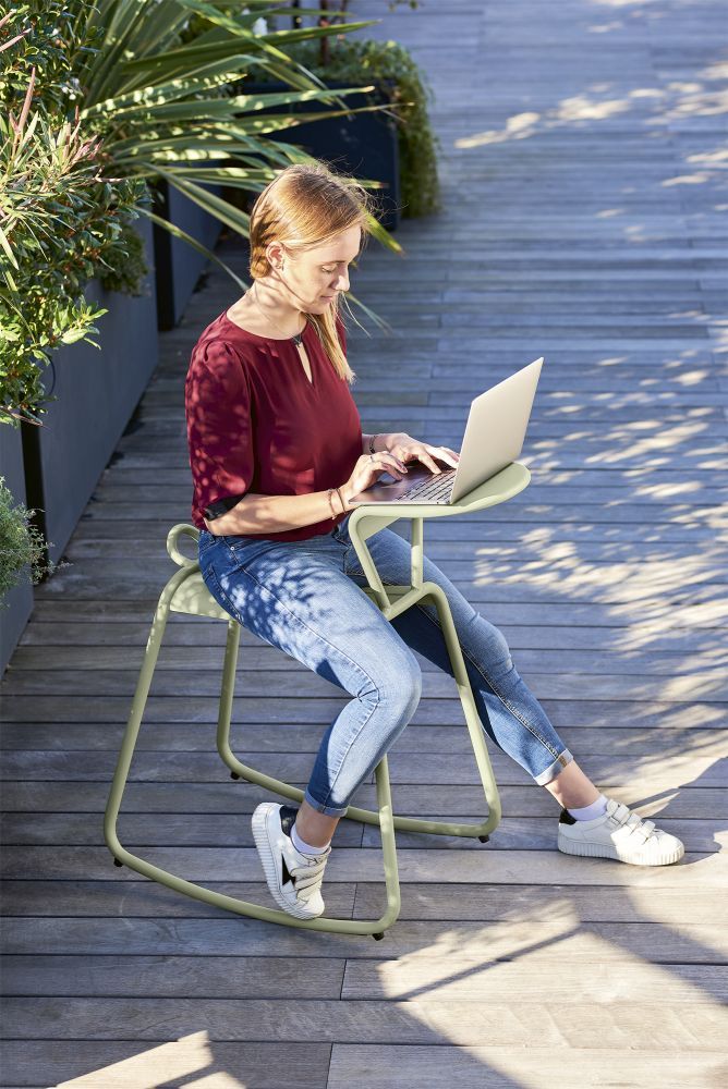 Frau arbeitet am Laptop auf einem Adadesk Beistelltisch von Fermob im Freien.