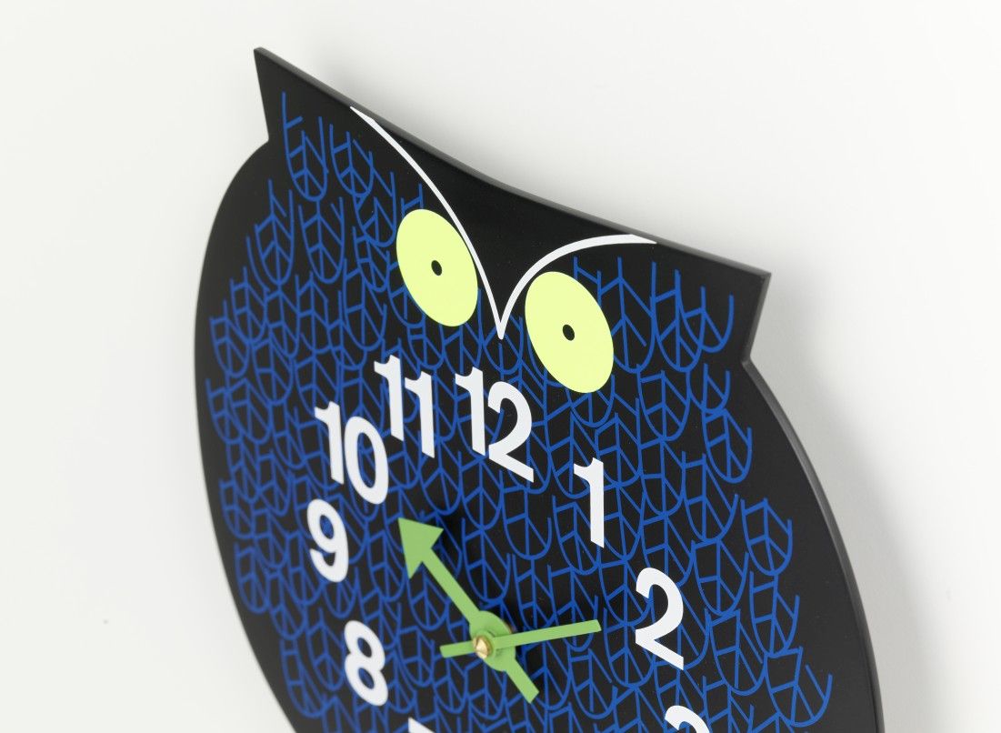Nahaufnahme der Omar the Owl Wanduhr von Vitra, Eule mit blauen Mustern und grünen Zeigern.