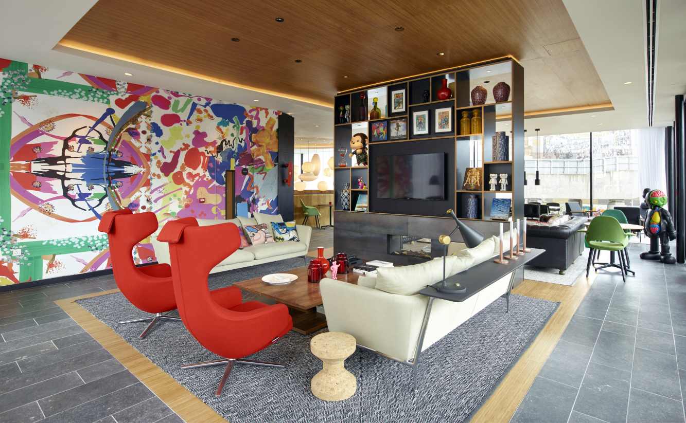 Wohnzimmer mit zwei roten Vitra Sesseln, Sofas, Couchtisch und Kunst an der Wand.
