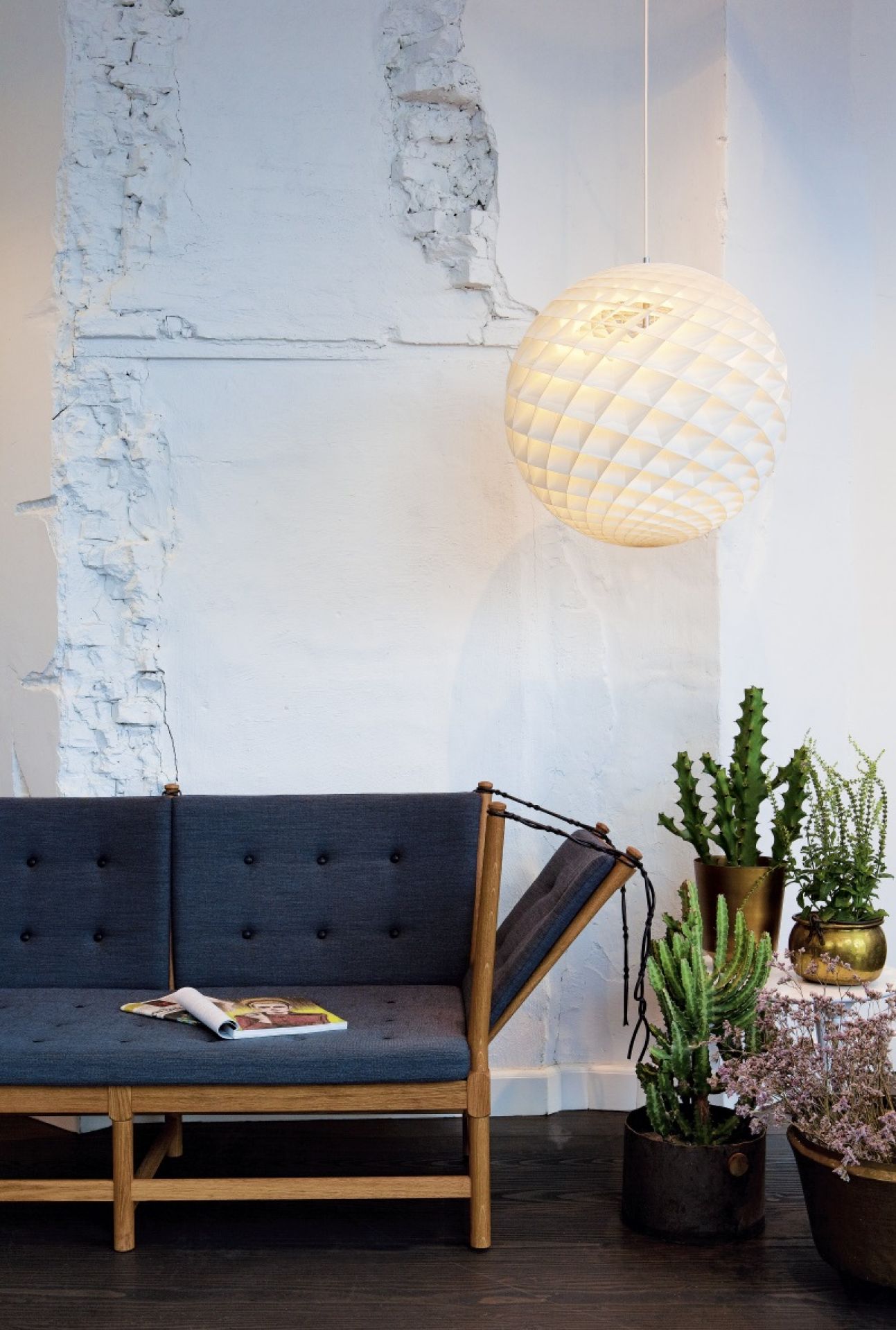 Weiße Patera Pendelleuchte von Louis Poulsen über einem Sofa mit Pflanzen im modernen Wohnzimmer.