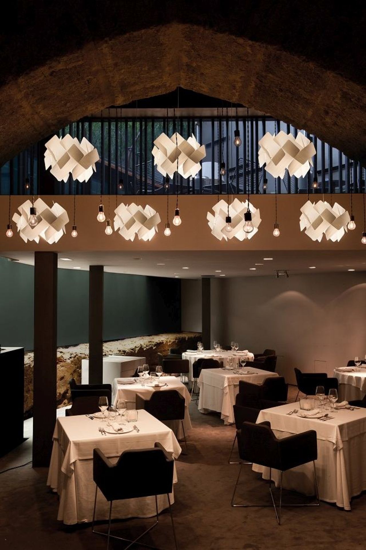 Mehrere kleine Escape LED Pendelleuchten von LZF Lamps über Tischen in einem Restaurant.