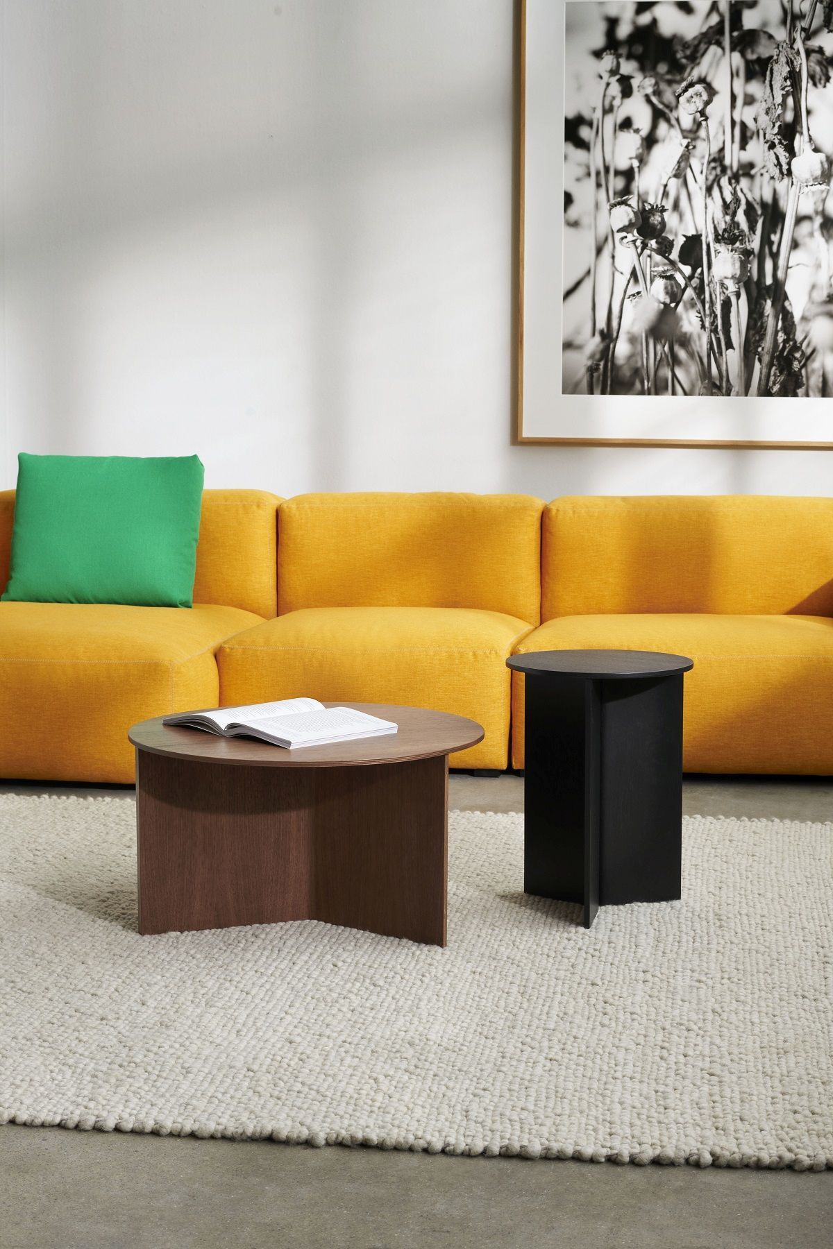 Hay Slit Table Wood Round XL Beistelltisch in Walnuss und Schwarz vor gelbem Sofa.