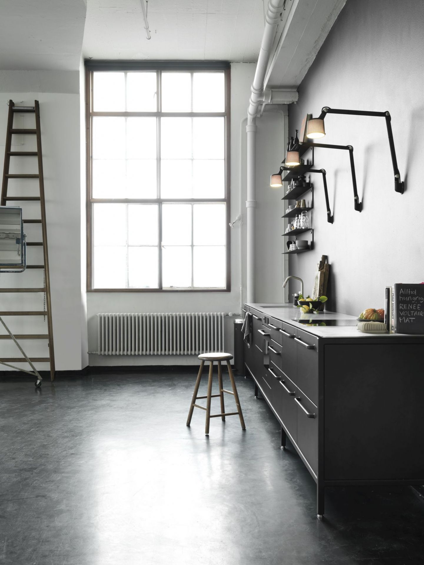 Moderne Küche mit Vipp Wandlampen, schwarzen Küchenschränken, Holzregal, Leiter und großem Fenster für stilvolle Innenarchitektur.