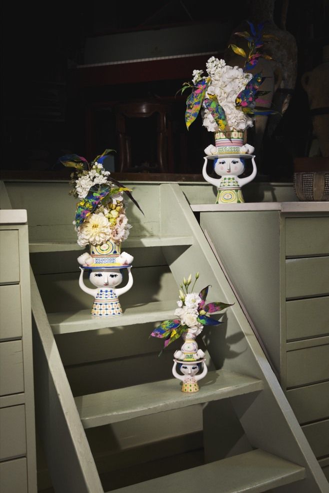 Drei Bjorn Wiinblad Kerzenständer "Lady with Hat" auf einer grünen Treppe mit Blumen dekoriert.