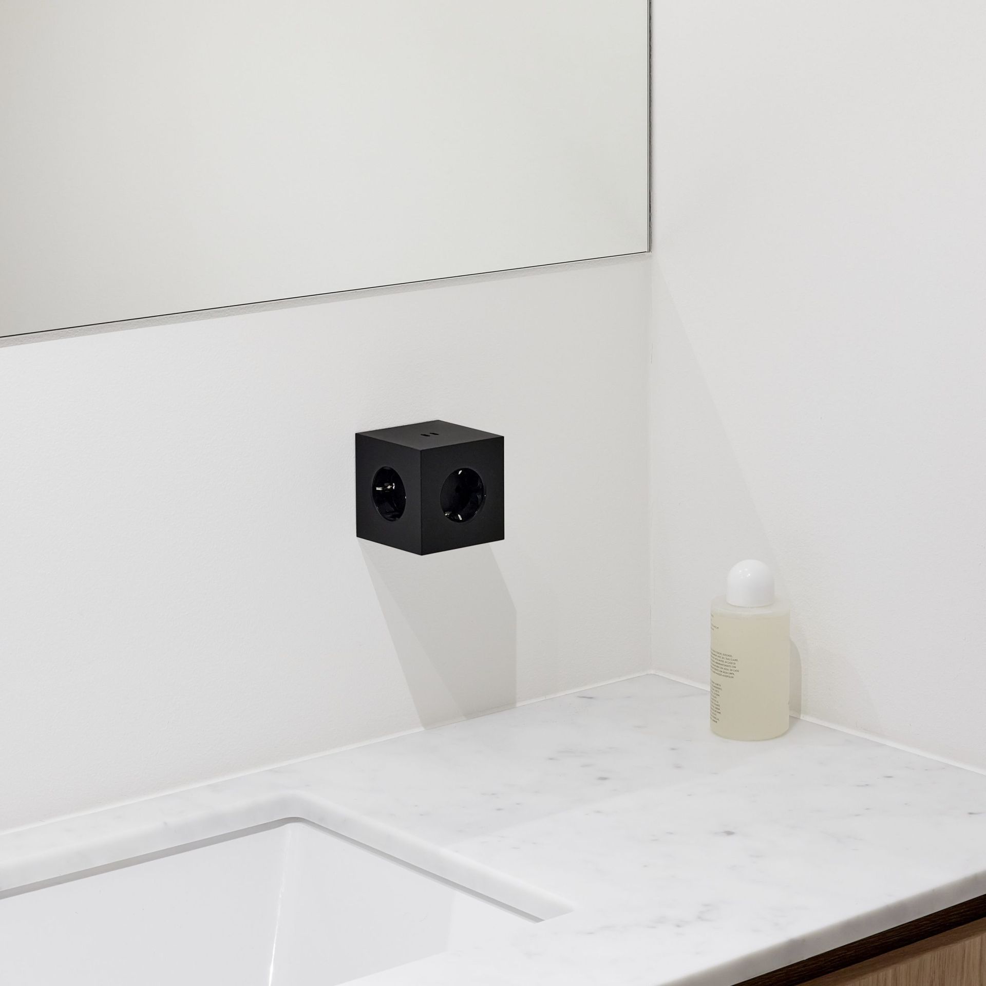 Schwarzer Avolt Square 2 Steckdosenwürfel mit USB-C an einer weißen Badezimmerwand.