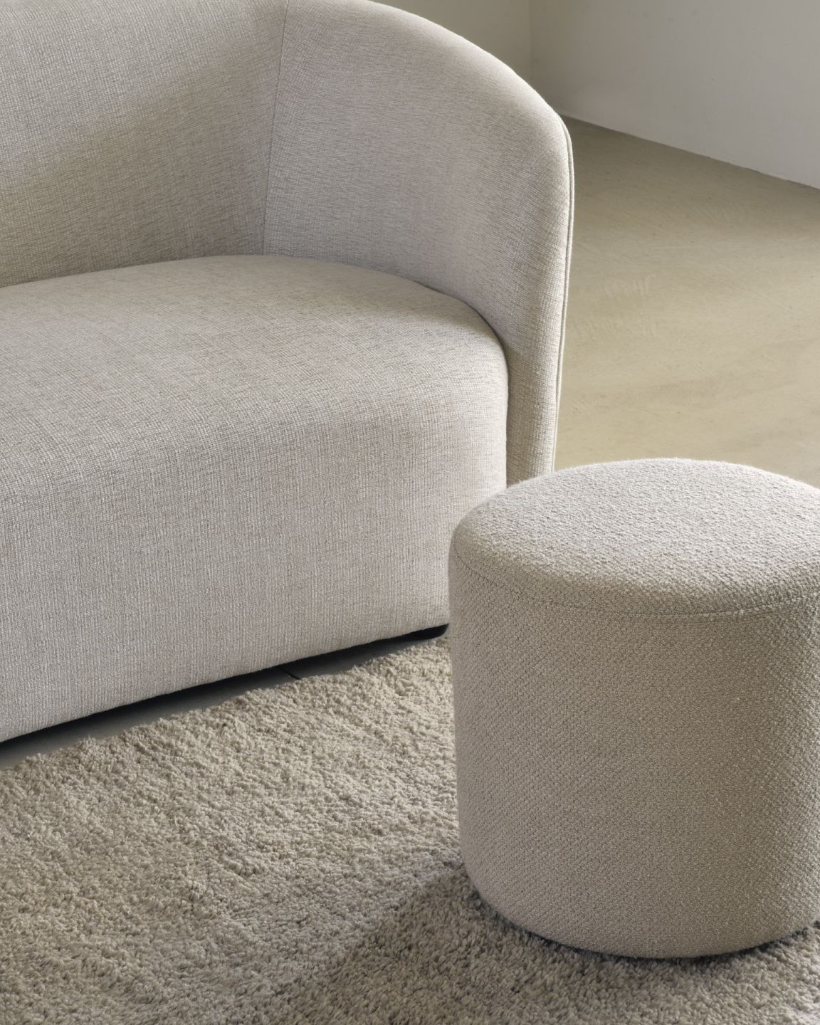 Heller Barrow Sitzhocker von Ethnicraft neben einem Sofa auf einem beigen Teppich.