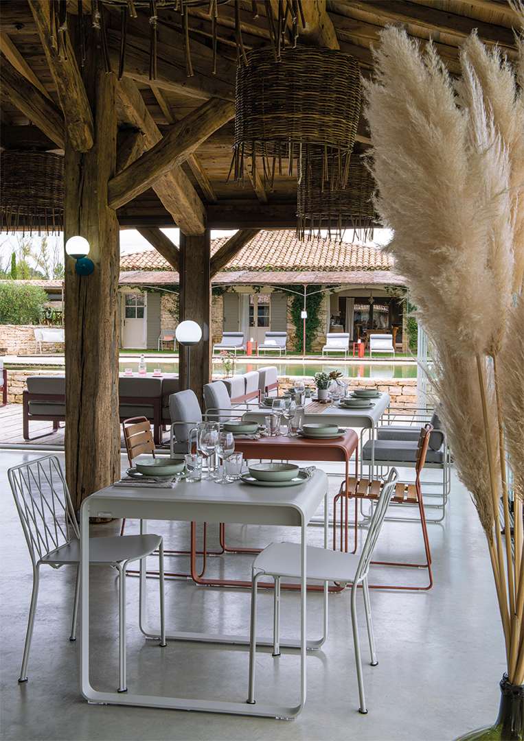 Fermob Bellevie Sessel im Outdoor-Bereich eines Restaurants mit Tischen, Stühlen und dekorativen Elementen.