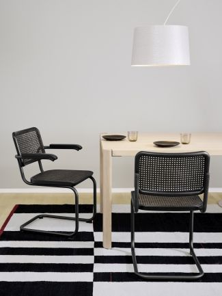 S 64 V Thonet Freischwinger Stühle mit Stahlrohrgestell und Wiener Geflecht an Esstisch auf Teppich.