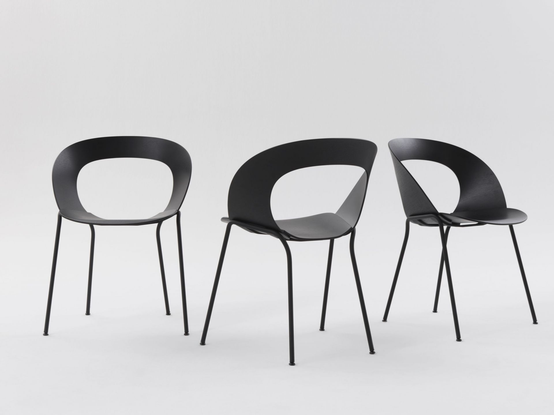 Drei schwarze Brunner Mudra Stühle mit minimalistischem Design und Stahlbeinen auf weißem Hintergrund.