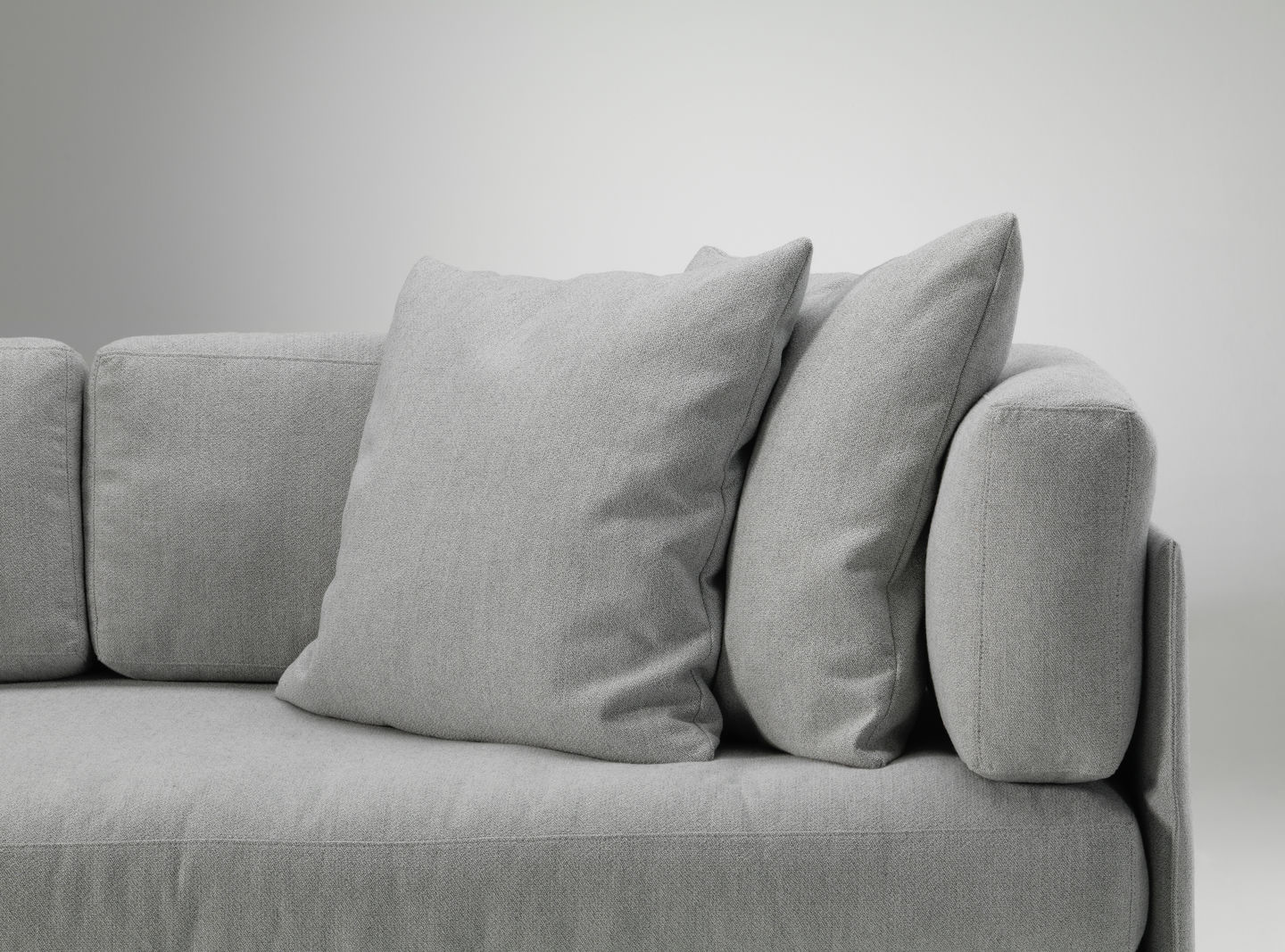 Graue Vitra Kissen auf einem grauen Sofa, modernes Wohnzimmer-Interieur mit Textilien.