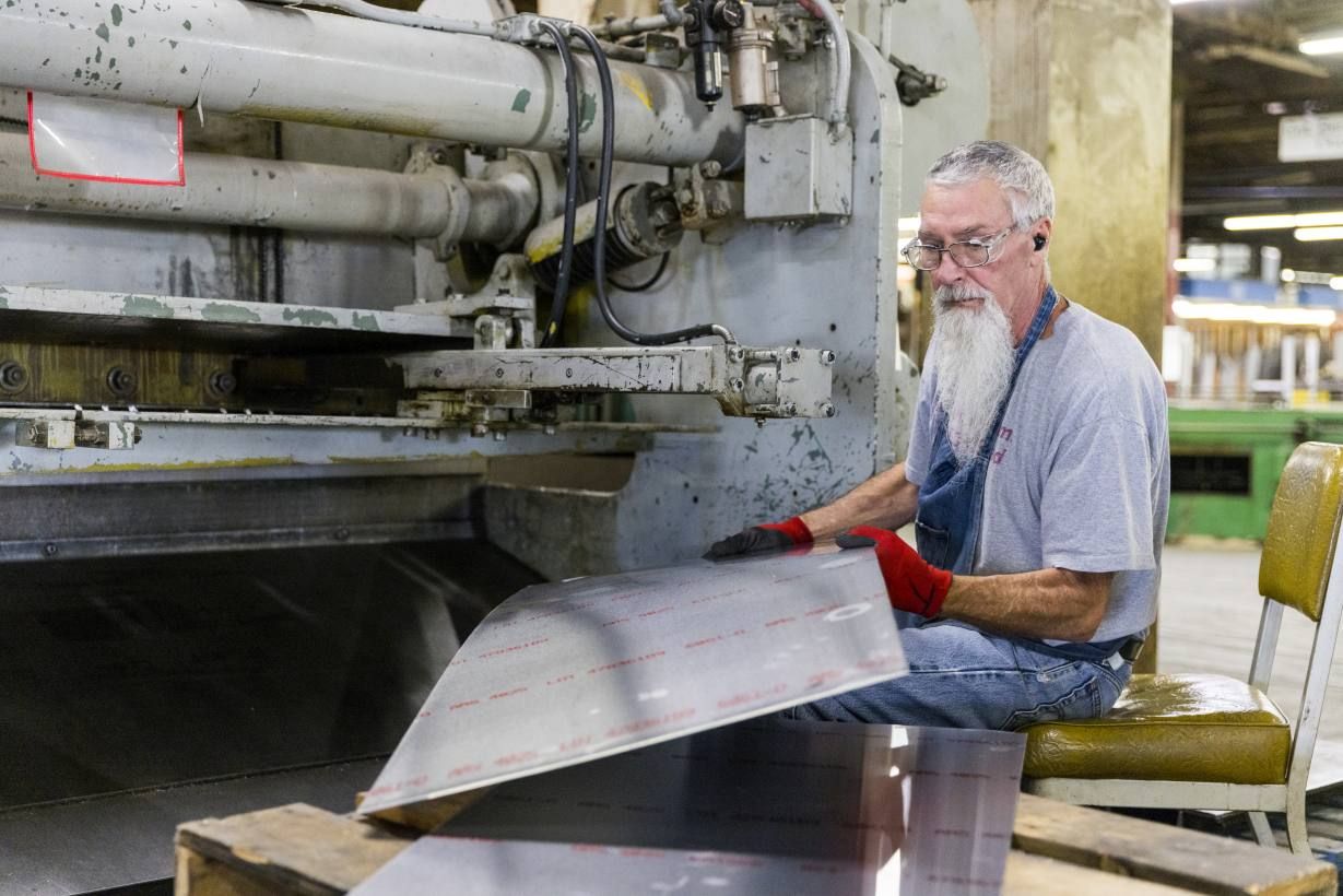 Mann fertigt Emeco Navy Chair Stuhl-Komponente aus Aluminium in einer Fabrik.