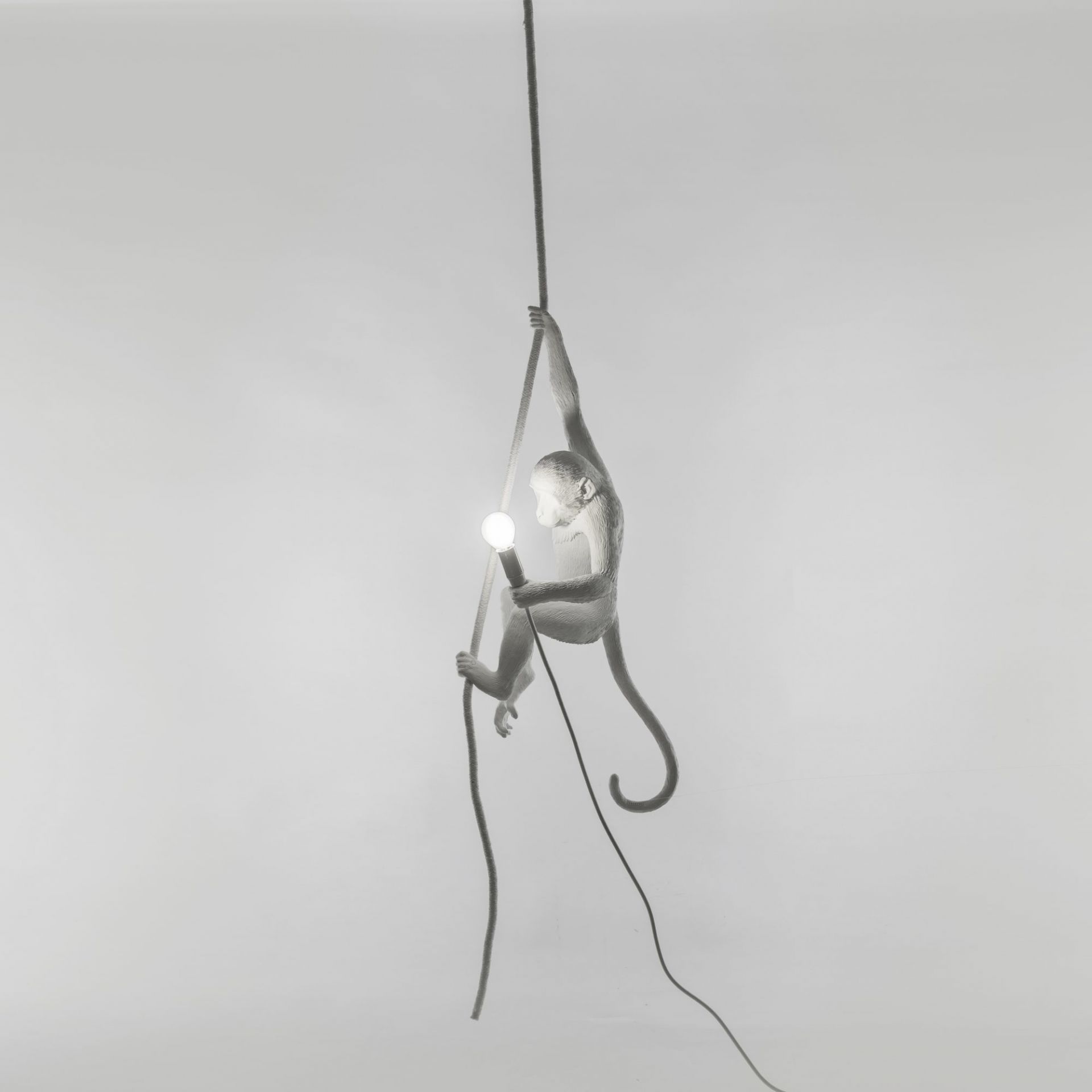 Weiße Monkey Lamp Pendelleuchte von Seletti, ein hängender Affe hält eine Glühbirne an einem Seil.