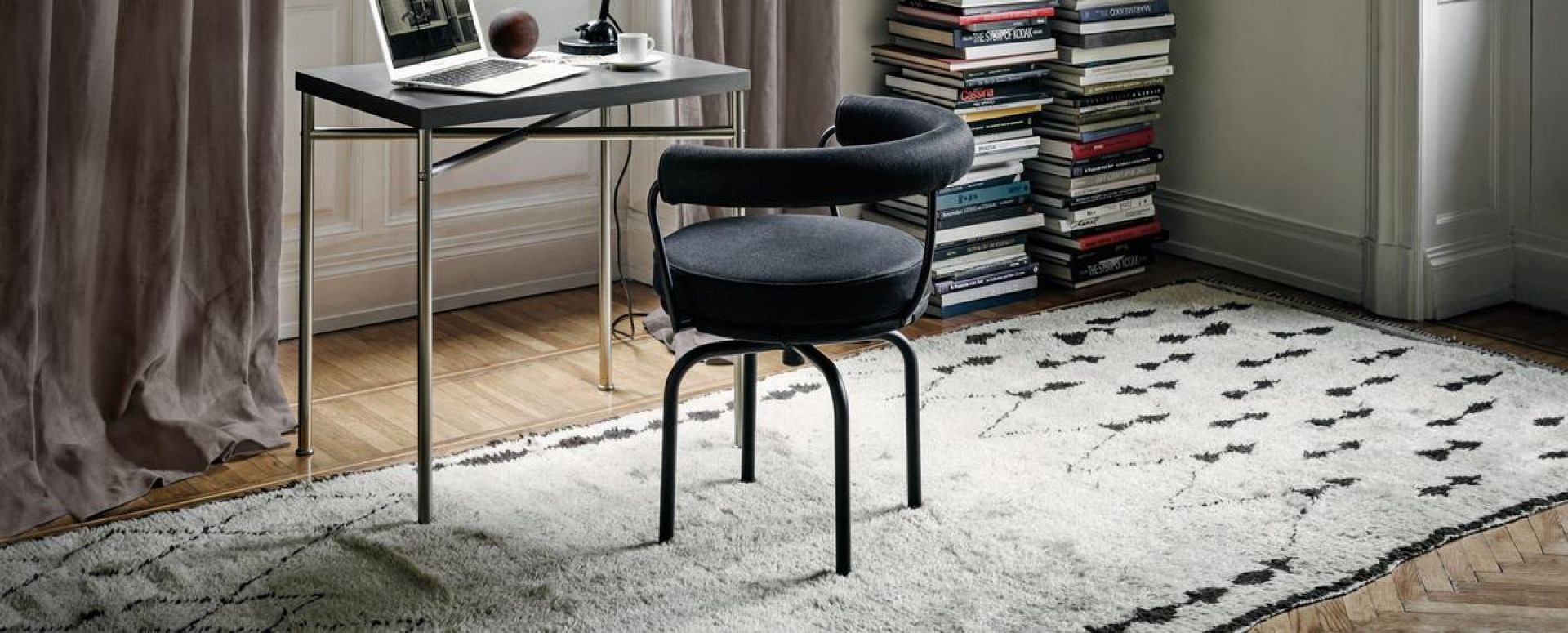 Schwarzer Cassina Drehsessel mit Armlehne am Schreibtisch auf Teppich. Moderner Design Drehstuhl.