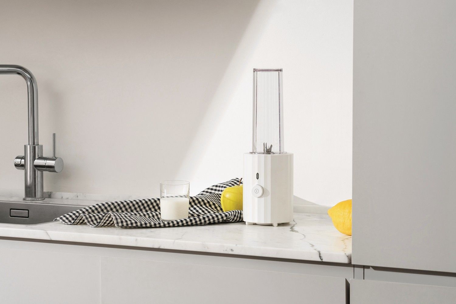 MDL17 Plissé Smoothie Maker von Alessi: Weißer Mini-Mixer mit Zitrone und Milch auf Marmor.