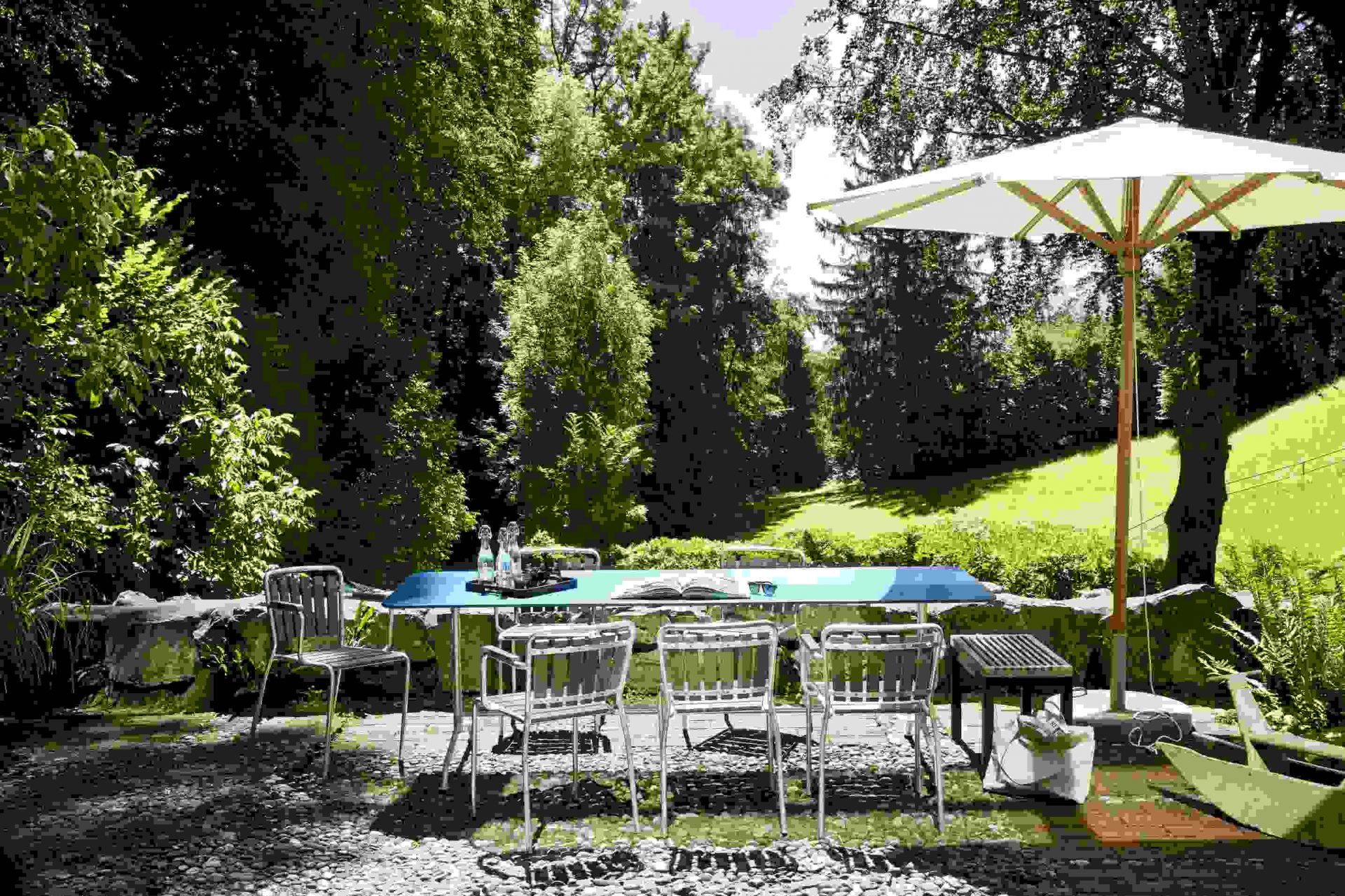 Haefeli Esstisch Outdoor in Graphitschwarz mit Stühlen und Sonnenschirm im Garten. Gartentisch für den Außenbereich.