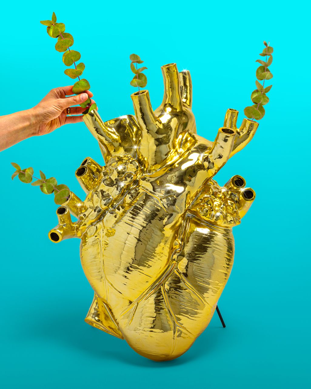 Goldene Love in Bloom Vase in Herzform mit Eukalyptus-Zweigen, extravagante Blumenvase für stilvolle Dekoration.