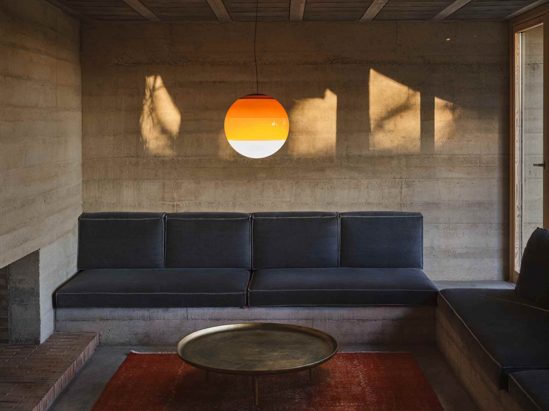 Dipping Light Pendelleuchte in Bernstein von Marset über Sofa. Moderne LED Lampe.
