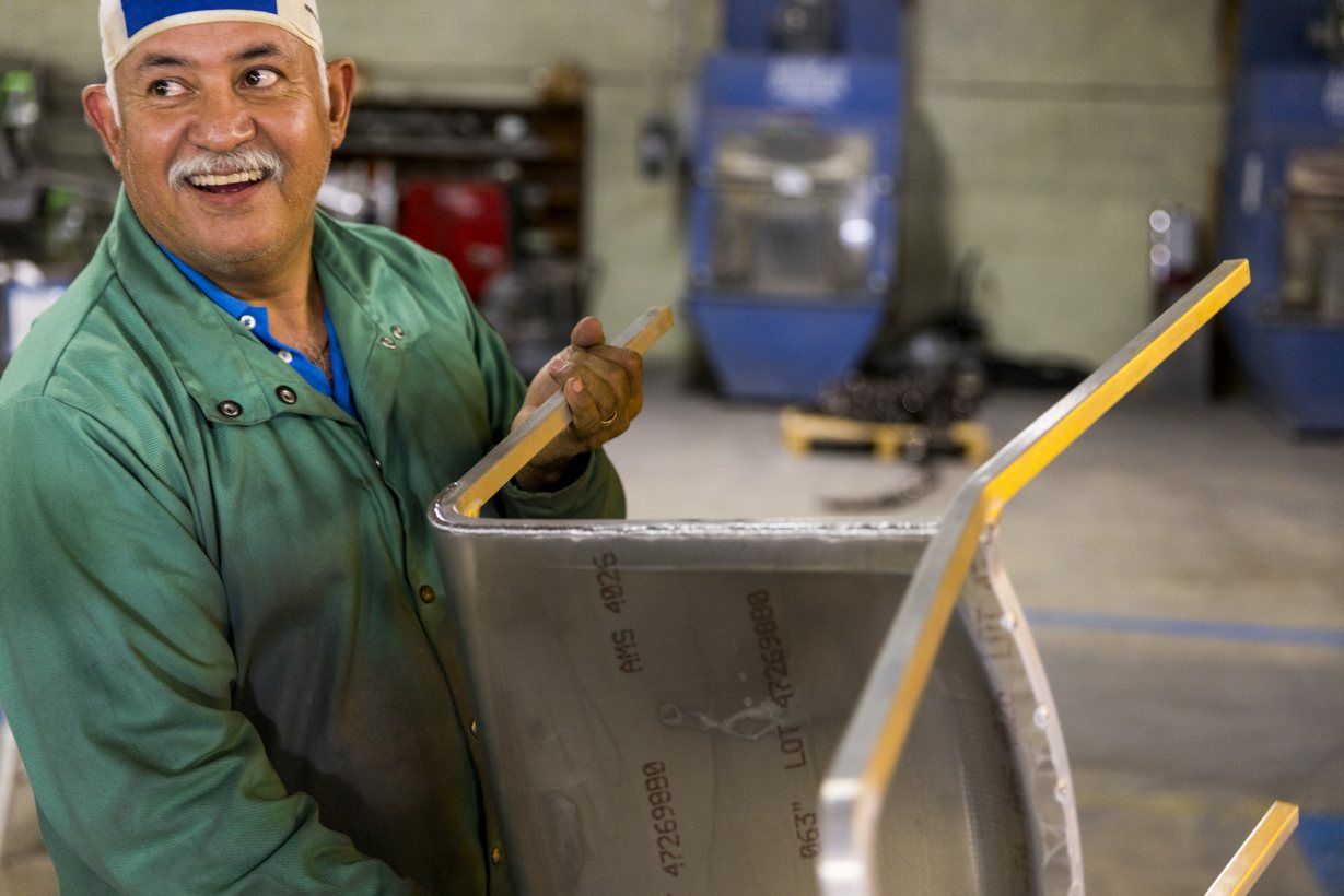 Ein Arbeiter fertigt einen Emeco Navy Chair Stuhl in einer Fabrik. Metallstuhl, Designklassiker.