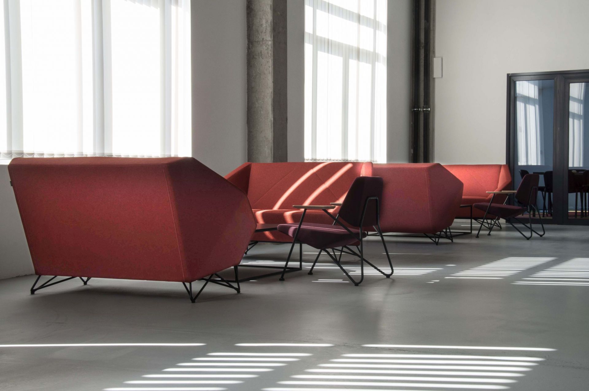 Rotes 3angle Sofa von Prostoria mit Stühlen in modernem Büro mit viel Tageslicht.