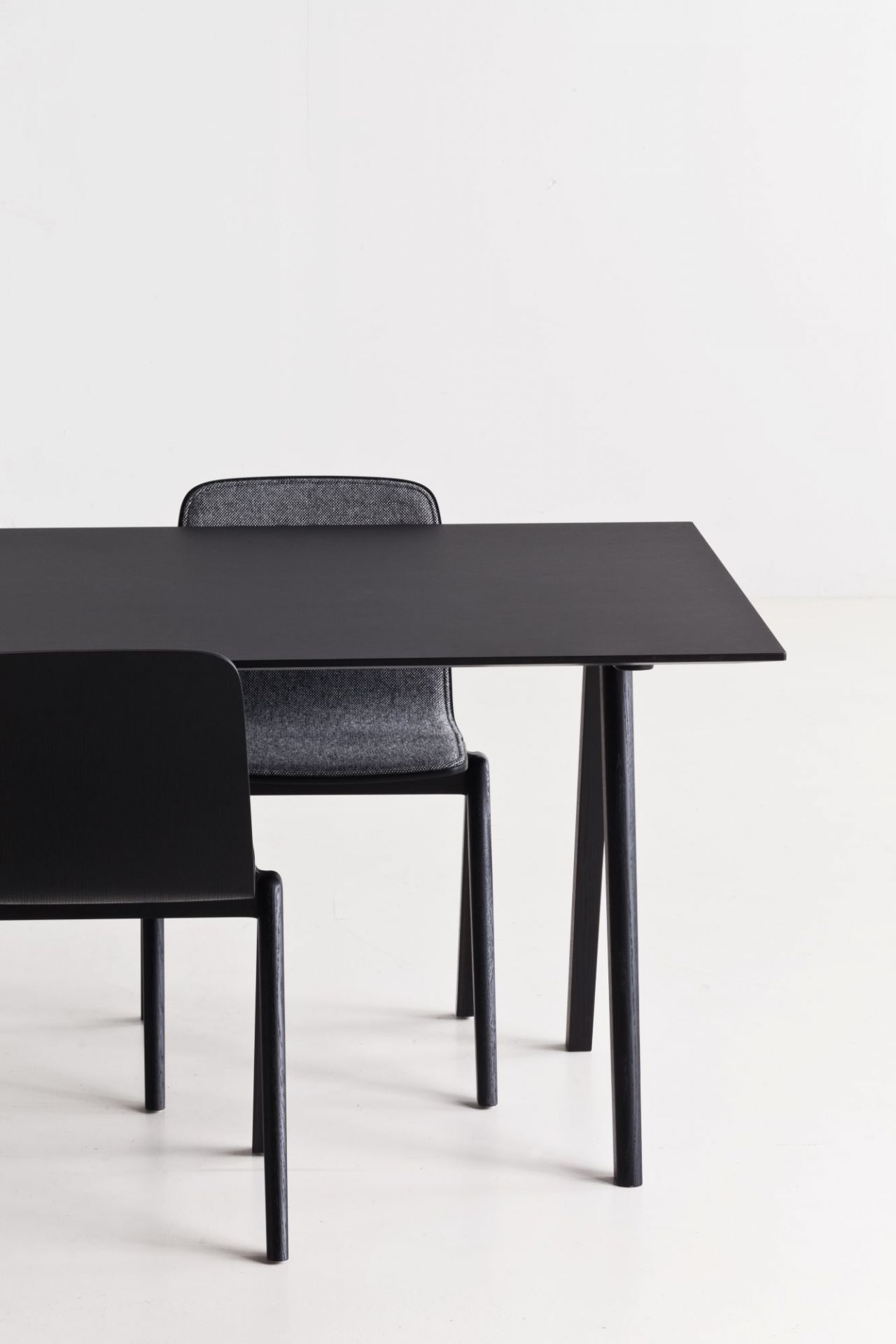 Schwarzer Copenhague Table CPH 10 Tisch von Hay mit zwei Stühlen vor weißem Hintergrund.
