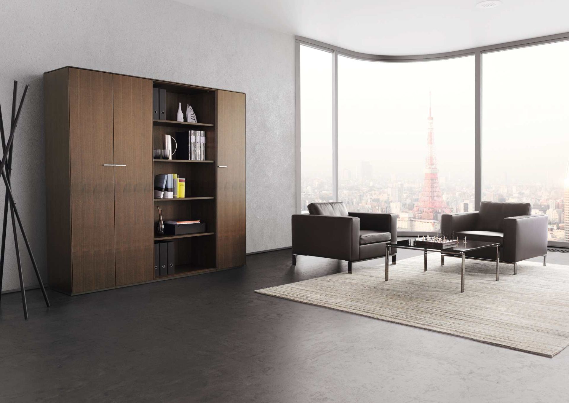 Moderner Walter Knoll Sessel 503 Foster in braunem Leder, mit Bücherschrank und Skyline im Hintergrund.