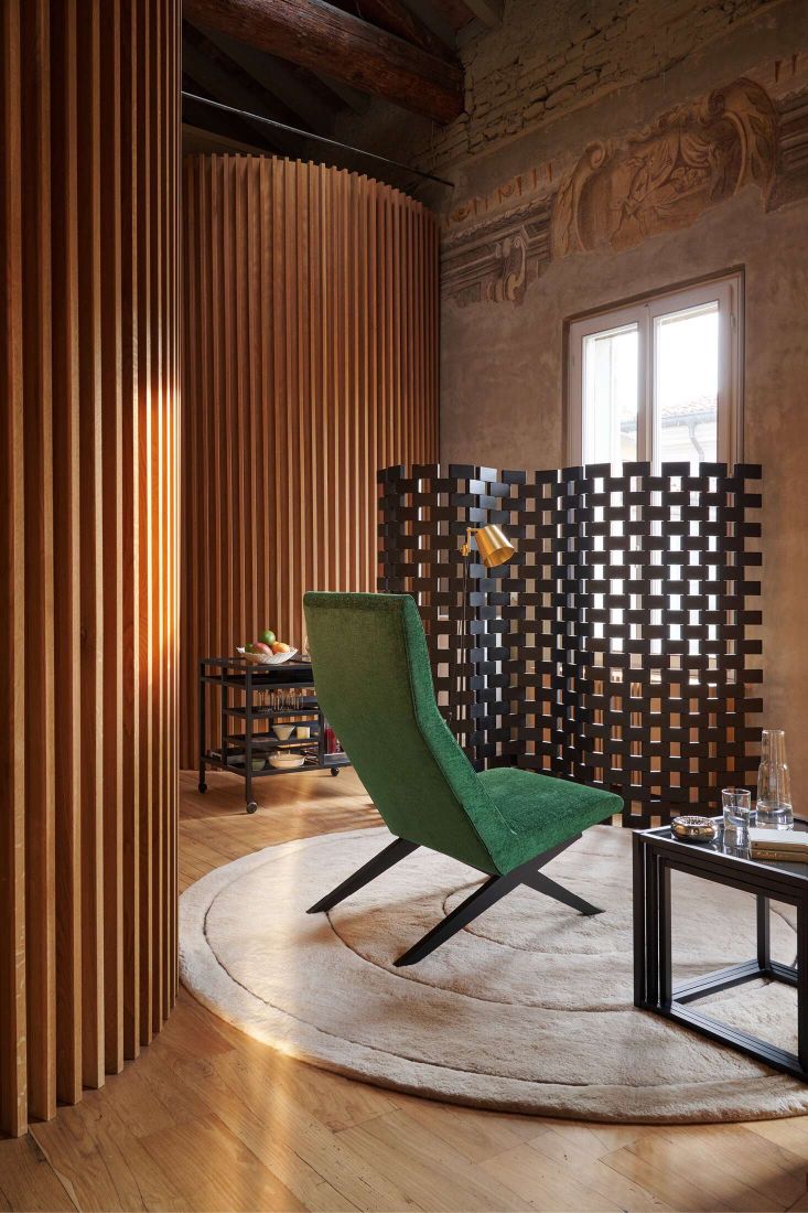 Innenaufnahme mit Cassina 537 Paravent Ambassade Raumteiler aus Holz, grüner Sessel und Beistelltisch.