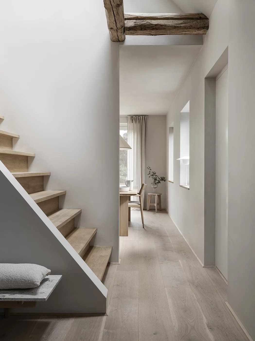 Heller Flur mit Holztreppe und Blomus Eli Hocker als Sitzgelegenheit am Esstisch im Hintergrund.