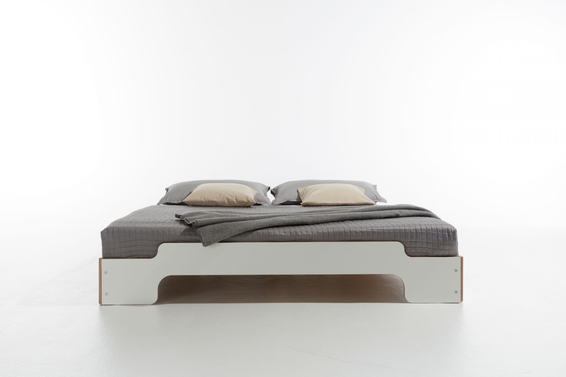 Weißes Stapelliege Bett von Müller Möbelwerkstätten mit grauer Bettwäsche und Kissen. Komfortable Schlafstätte.