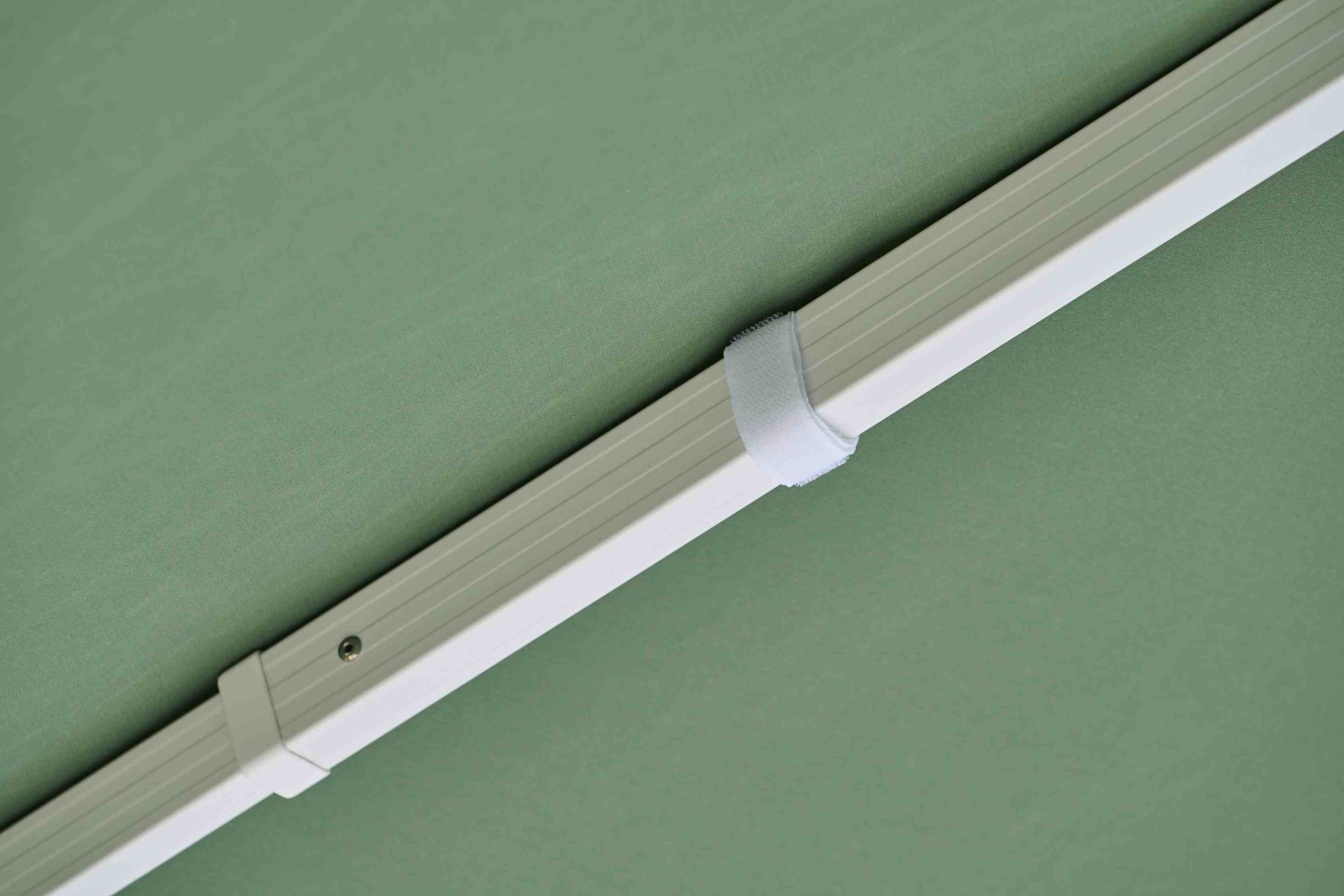 Detailaufnahme des Weishäupl Sonnenschirms in Grün, der weiße Rahmen und ein Klettband sind sichtbar.