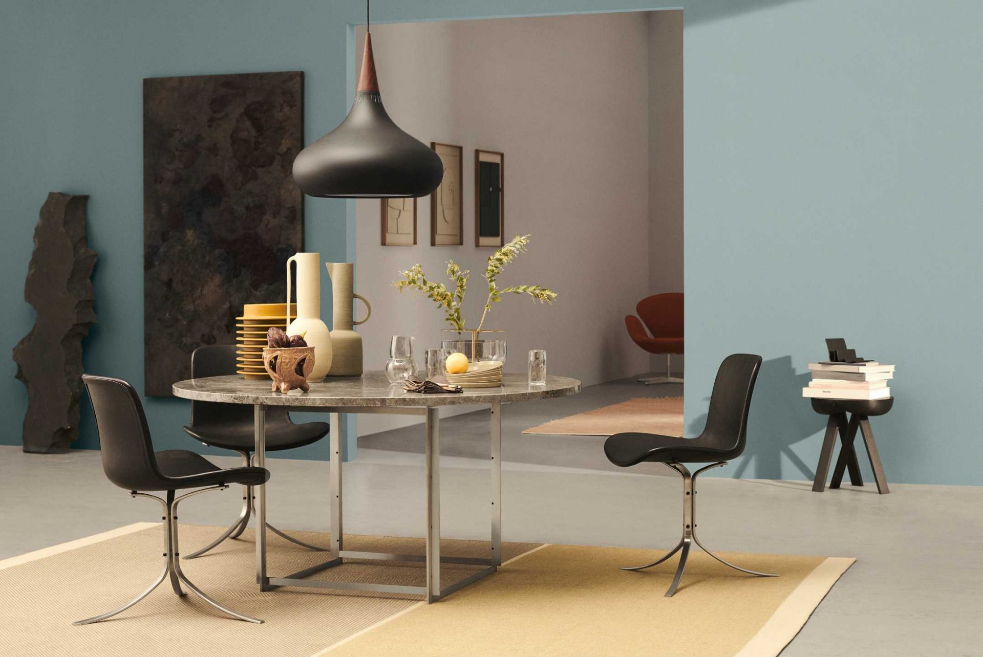 Esszimmer-Szene mit Fritz Hansen PK9 Stühlen in Schwarz um einen runden Marmortisch.