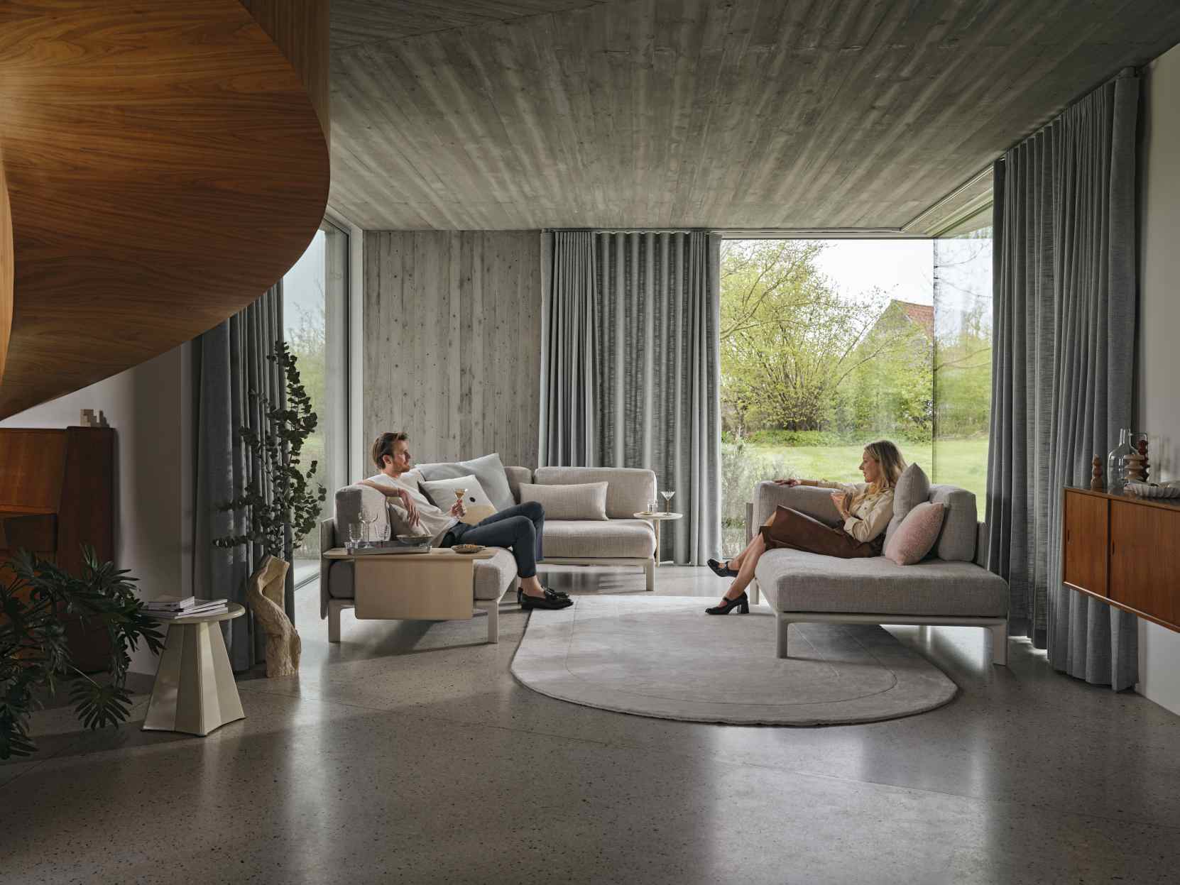 Helle Wohnzimmer-Szene mit zwei modularen Sofas, verbunden mit Vitra Anagram Plattformverbindern, für flexible Sitzanordnungen.