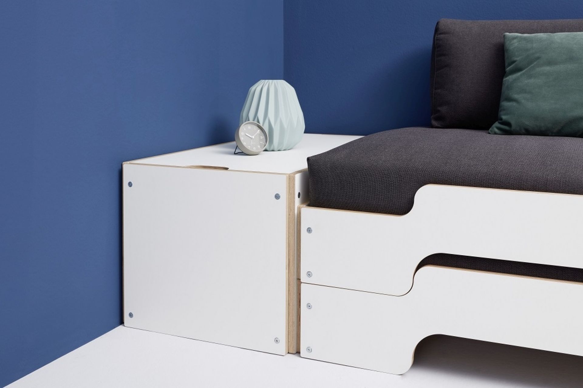 Weißer Bettkasten mit Deckel von Müller Möbelwerkstätten neben einem modularen Bett. Stauraum für Schlafzimmer.