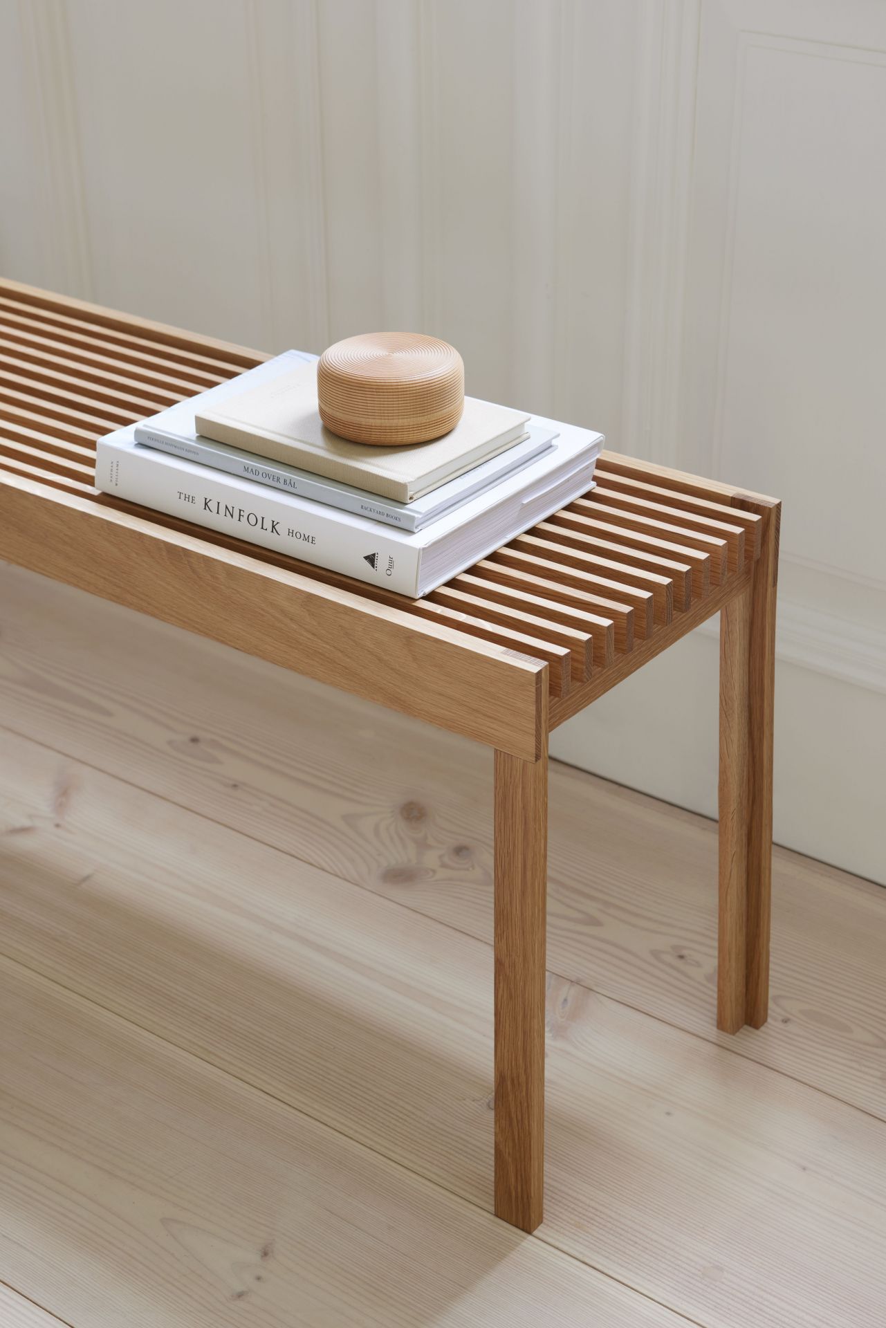 Leichte Eichenbank mit geölter Oberfläche, Bücher und Holzobjekt darauf, minimalistisches Design für Wohnzimmer und Flur.