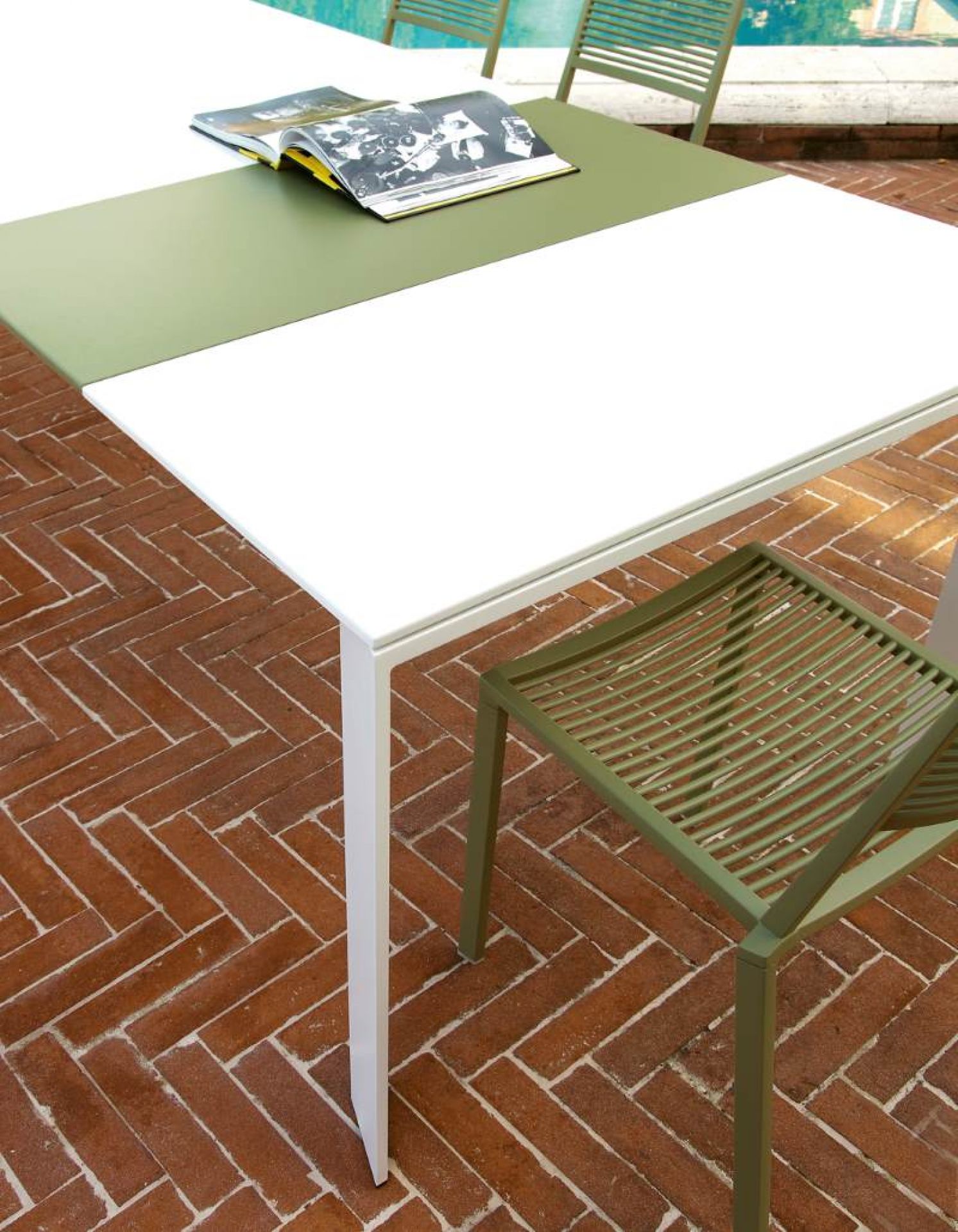 Grande Arche Outdoor Tisch von Fast, Gartentisch mit weißer und grüner Tischplatte, Stuhl im Hintergrund.