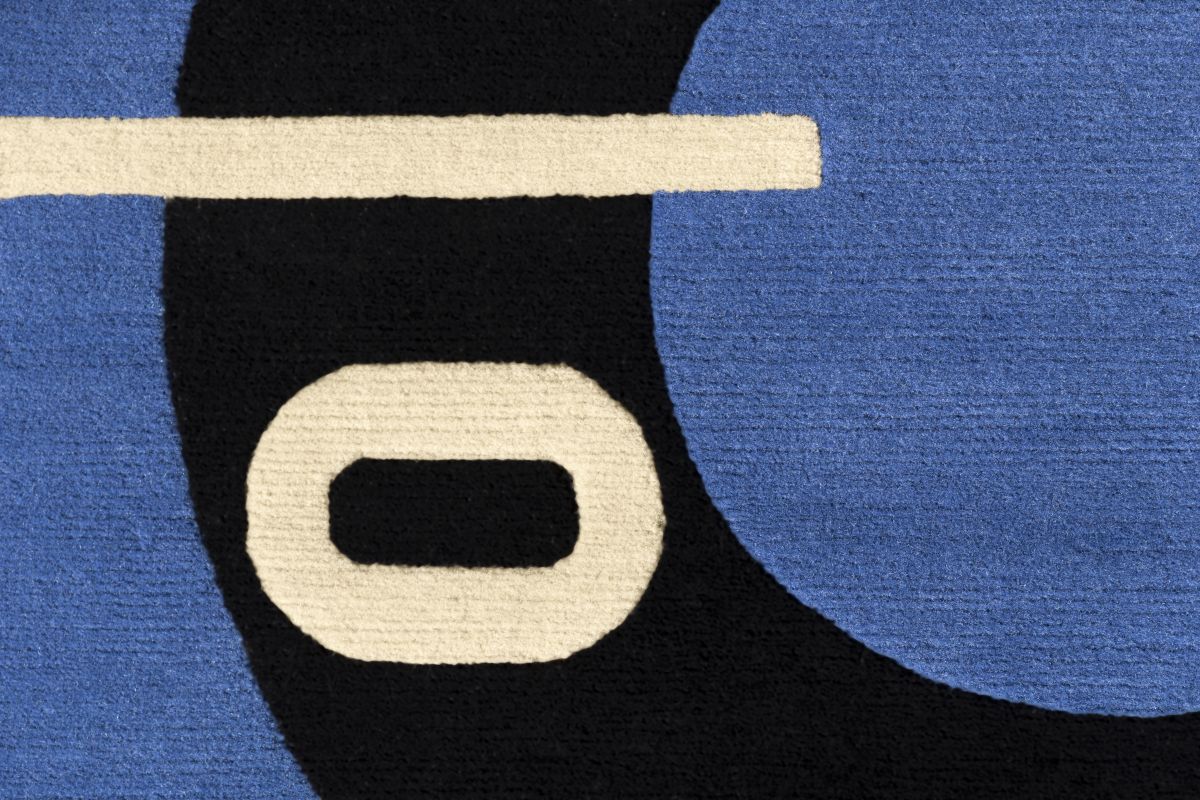 Detailaufnahme Blue Marine Teppich mit abstraktem Muster in Blau, Schwarz und Creme.