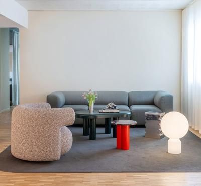 Wohnzimmer mit grauem Sofa, Sessel und Normann Copenhagen Dit Coffee Table Beistelltisch in Rot und Grau.