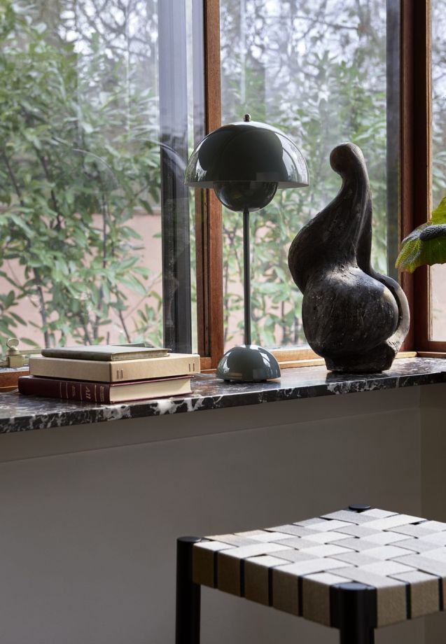 Graue Flowerpot Tischleuchte von AndTradition auf einer Fensterbank neben Büchern und einer Skulptur.