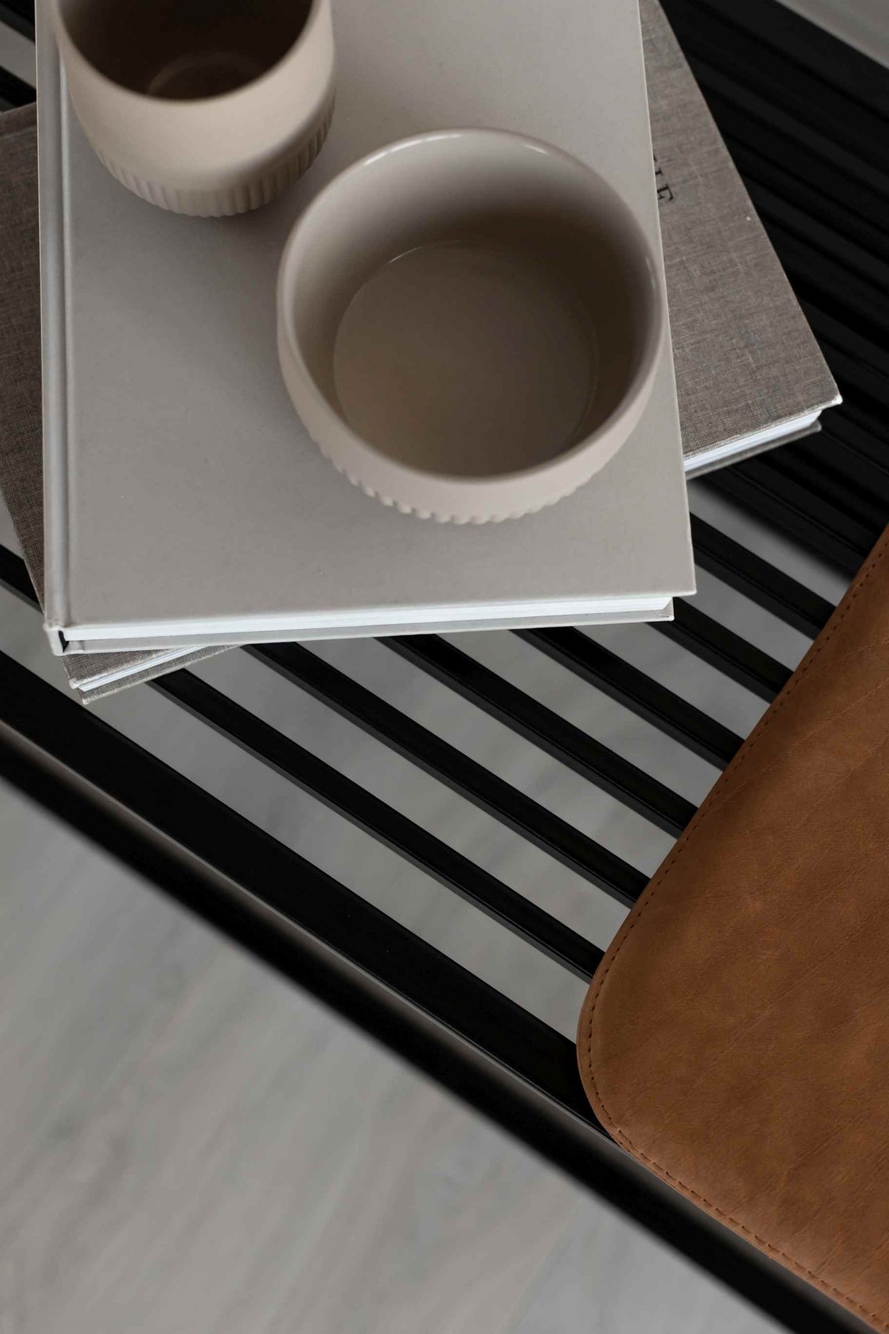 Detailaufnahme der Element Bench Bank von Novoform mit Deko-Schalen und Büchern auf den schwarzen Metallstreben.