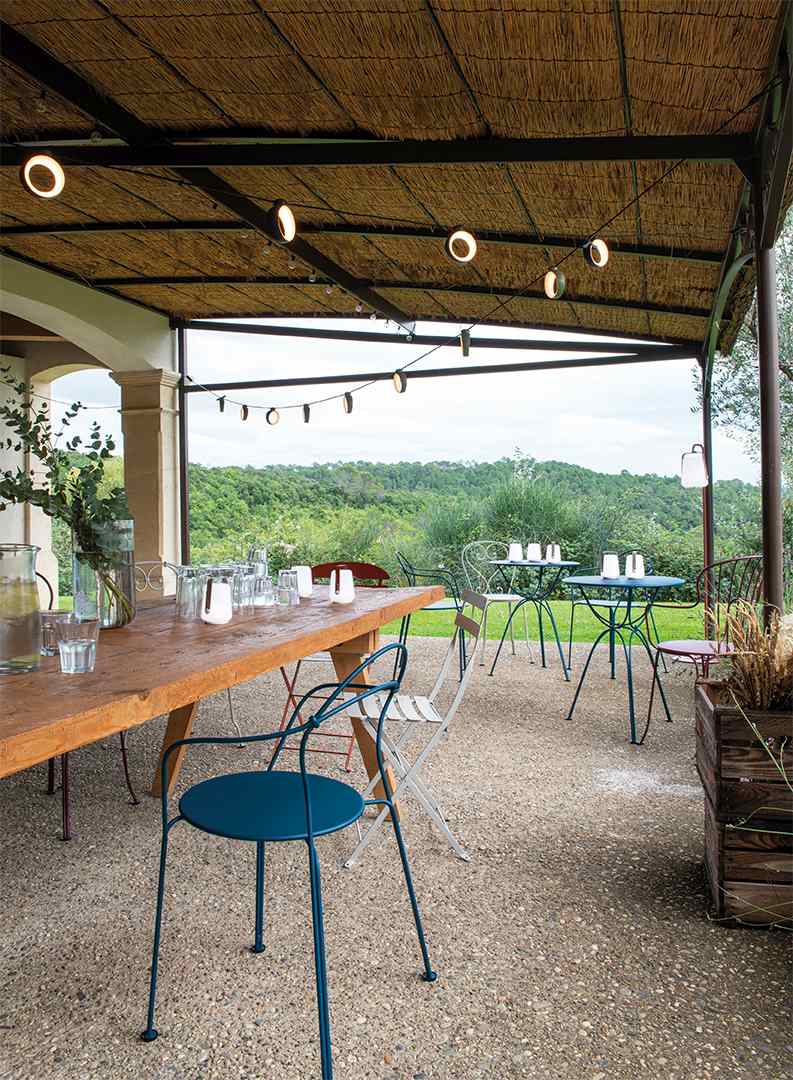 Airloop Tisch von Fermob: Blauer Outdoor-Tisch Ø 60 cm auf einer Terrasse mit Gartenblick.