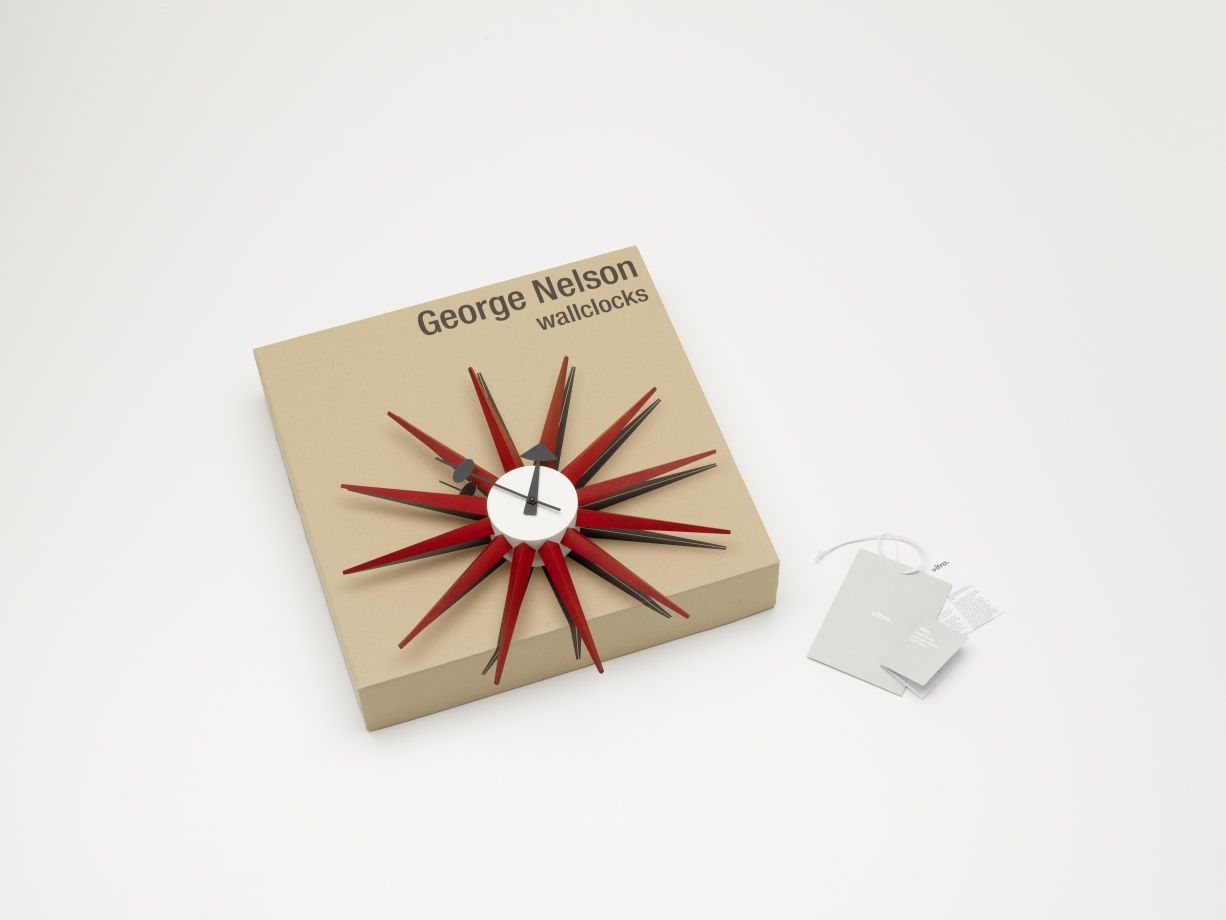 Rote Sunburst Clock Wanduhr von Vitra auf Kartonverpackung, modernes Designobjekt für die Wand.