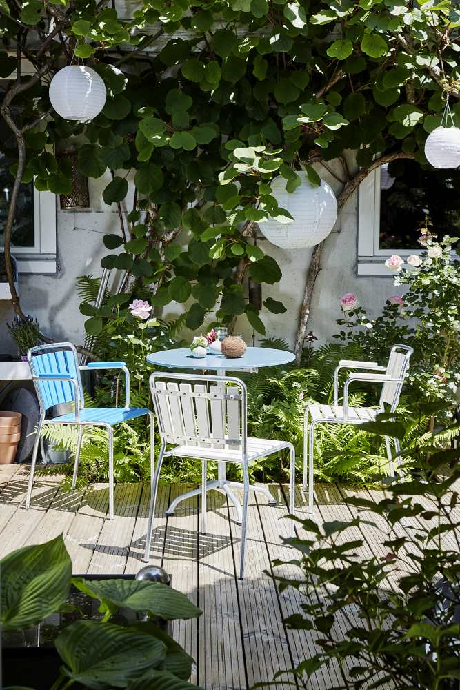 Graublauer Haefeli Gartentisch Ø 90 cm mit Stühlen auf einer Holzterrasse im Garten. Outdoor-Möbel für den Sommer.