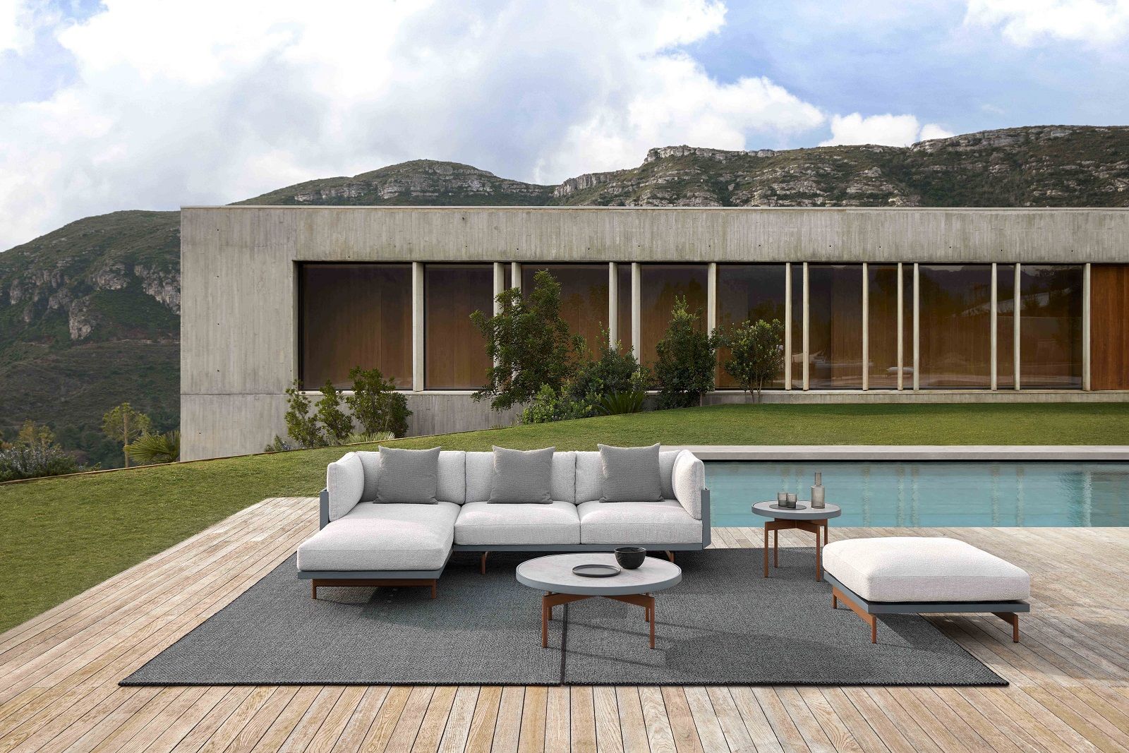 Grauer Saline Outdoor Rug Teppich von Gan unter einer Lounge-Gruppe auf einer Holzterrasse am Pool.