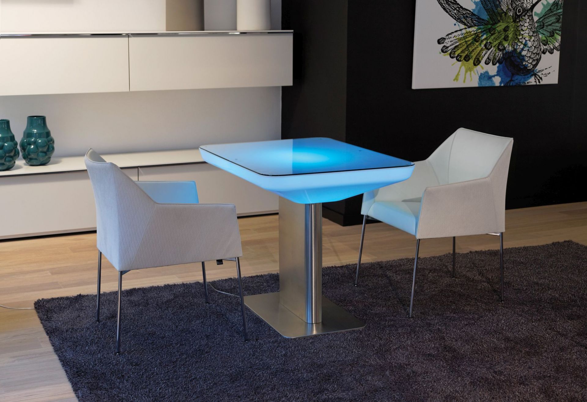 Studio 75 LED Tisch mit blauer Beleuchtung und zwei Stühlen auf einem Teppich.