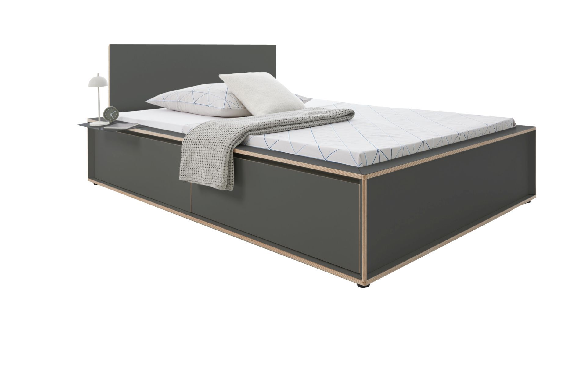 Graues Spaze Bett von Müller Möbelwerkstätten mit Nachttisch, Kissen und Decke.