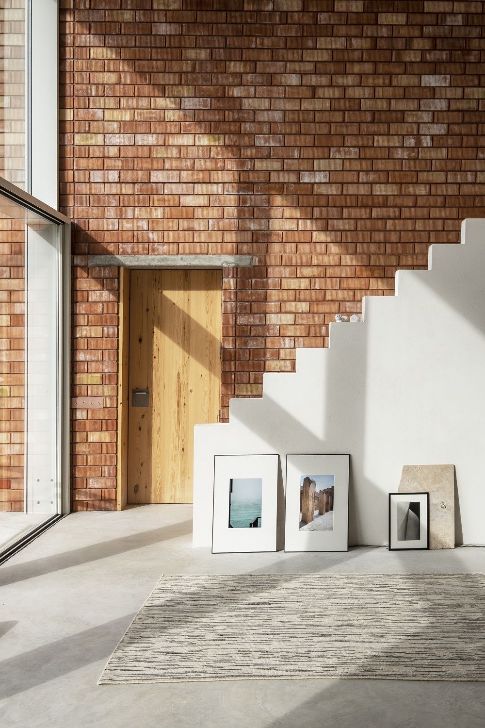 Doblecara Rug Teppich von Nanimarquina in hellem Raum mit Ziegelwand und Treppe. Moderner Teppich.